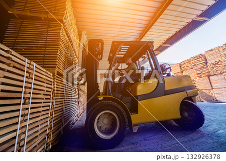 Forklift loader load lumber into a dry kiln. Wood drying in containers. Forklift loader load lumber into a dry kiln. Wood drying in containers. 132926378