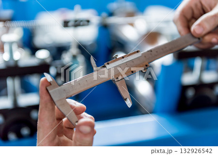 Male hands hold vernier caliper and measure steel collar. 132926542