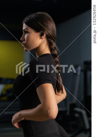A female athlete stands tall against the backdrop of running tracks showcasing her athletic build. She is focused and ready for her training session wearing stylish sports attire. A female athlete stands tall against the backdrop of running tracks showcasing her athletic build. She is focused and ready for her training session wearing stylish sports attire. 132926956