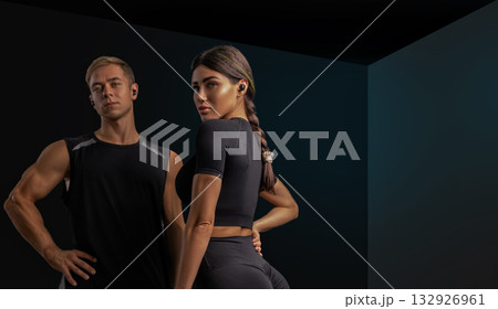 A man and a woman stand together in a sleek gym both dressed in athletic gear. They exude confidence and motivation ready to tackle their workout goals. A man and a woman stand together in a sleek gym both dressed in athletic gear. They exude confidence and motivation ready to tackle their workout goals. 132926961
