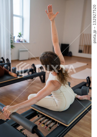 Pilates group of Women doing mermaid exercise in a sunlite modern studio, embodying calm, focus, and strength. Pilates group of Women doing mermaid exercise in a sunlite modern studio, embodying calm, focus, and strength. 132927520