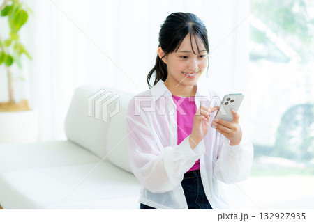 部屋でスマホを操作する若い女性 部屋でスマホを操作する若い女性 132927935