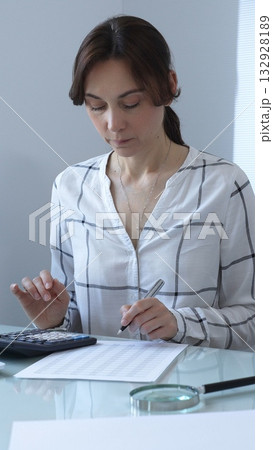 Female professional calculating finances, reviewing paperwork, tracking business expenses with precision and focus. Audit and taxes in business Female professional calculating finances, reviewing paperwork, tracking business expenses with precision and focus. Audit and taxes in business 132928189