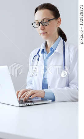 Female doctor is typing on a laptop in a bright medical office, showcasing healthcare technology and medical documentation. Medicine and health care concept Female doctor is typing on a laptop in a bright medical office, showcasing healthcare technology and medical documentation. Medicine and health care concept 132928271