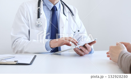 Close-up of doctor man showing information on tablet to patient woman during medical visit, explaining diagnosis and treatment options, providing medical consultation. Medicine concept Close-up of doctor man showing information on tablet to patient woman during medical visit, explaining diagnosis and treatment options, providing medical consultation. Medicine concept 132928280