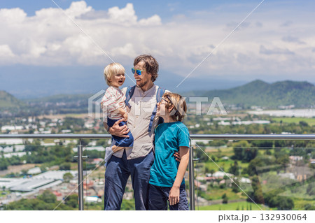 Father with his two sons standing in front of Popocatepetl volcano in Mexico, surrounded by clouds, enjoying a scenic family adventure and breathtaking outdoor view Father with his two sons standing in front of Popocatepetl volcano in Mexico, surrounded by clouds, enjoying a scenic family adventure and breathtaking outdoor view 132930064