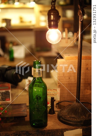 裸電球の灯りが照らすビール瓶とカフェの落ち着いた雰囲気  132931751