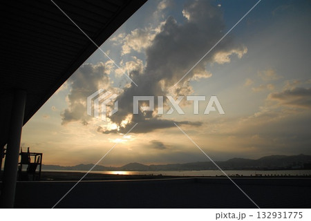 夕日に染まる雲間と海越しの山並みを屋根越しに望む景色 夕日に染まる雲間と海越しの山並みを屋根越しに望む景色 132931775