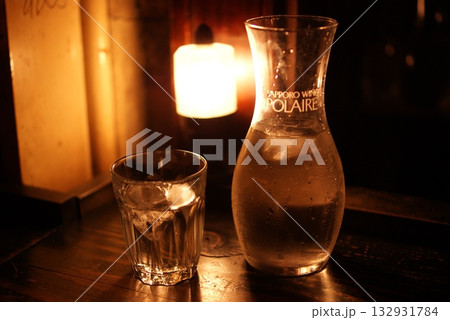 ランプの灯りが映す氷入りグラスとカラフェの夜の一杯 ランプの灯りが映す氷入りグラスとカラフェの夜の一杯 132931784