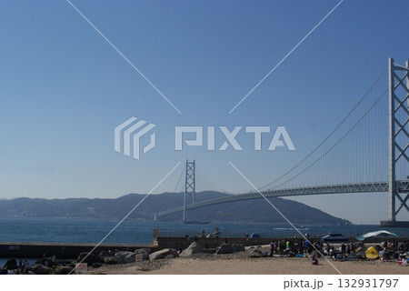 砂浜で過ごす人々と遠くに佇む明石海峡大橋の夏景色  132931797