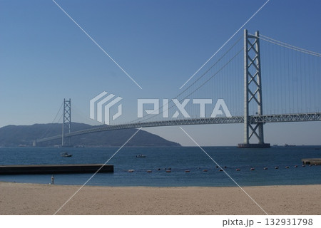 静謐な海面に浮かぶ小舟と明石海峡大橋の調和  132931798