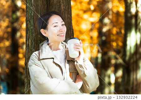 紅葉を楽しみながらホットドリンクを飲む女性 ライフスタイルイメージ 紅葉を楽しみながらホットドリンクを飲む女性 ライフスタイルイメージ 132932224