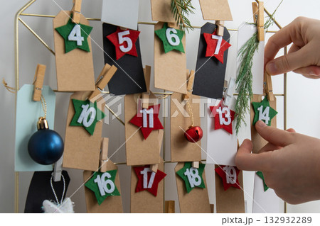 Number on craft paper notes with tasks before Christmas holidays. Female making kraft paper for handmade advent calendar Made with your own hands step by step DIY Number on craft paper notes with tasks before Christmas holidays. Female making kraft paper for handmade advent calendar Made with your own hands step by step DIY 132932289