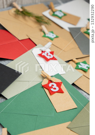 Number on craft envelopes notes with tasks before Christmas holidays. Female making kraft paper for handmade advent calendar Made with your own hands step by step DIY 132932290