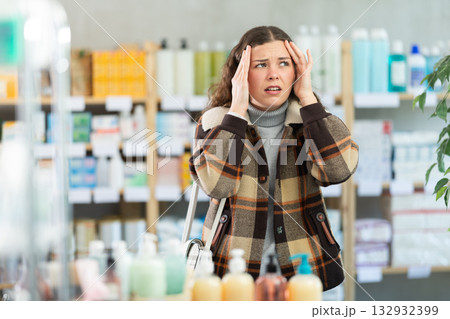 Girl in winter clothes suffers from headache, while visiting household goods supermarket Girl in winter clothes suffers from headache, while visiting household goods supermarket 132932399