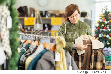 Woman is busy looking at clothes items in store, she choose plaid jacket, X mas Eve 132932415