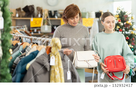 Teen girl with mum picks up clothes and choose handbag, New Year Eve sale Teen girl with mum picks up clothes and choose handbag, New Year Eve sale 132932417