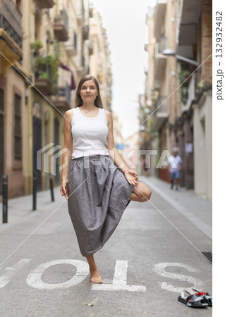 Woman in midst of bustle of city in pose of tree asana Woman in midst of bustle of city in pose of tree asana 132932482
