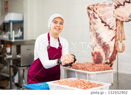 Young female butcher preparing minced meat for sale 132932902
