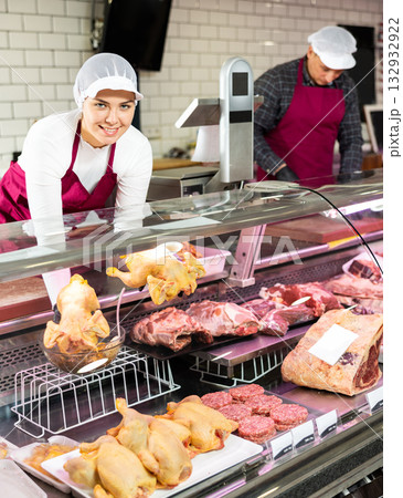 Female butcher laying broiler chickens in display case 132932922