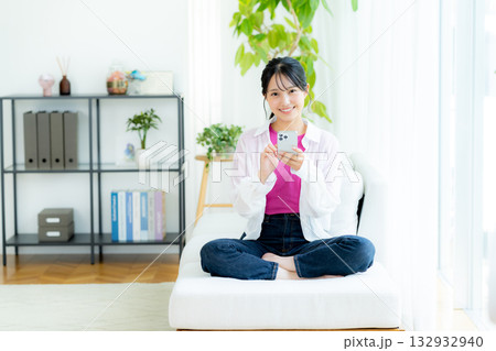 部屋でスマホを操作する若い女性 132932940