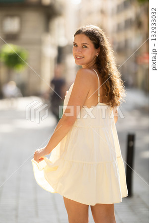 Young woman walks along city street 132933032