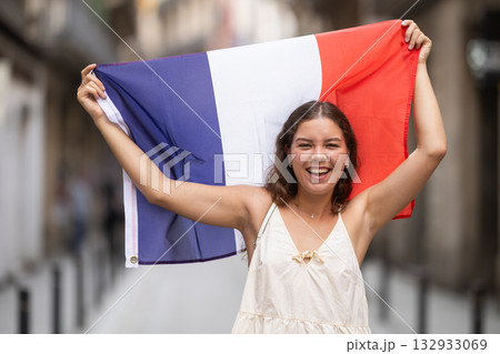 Woman waving France flag on street of summer European city 132933069