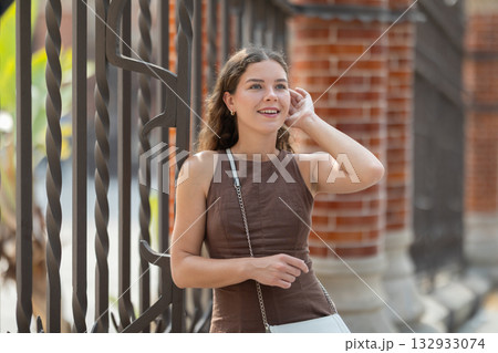 Young woman standing near the metal fence Young woman standing near the metal fence 132933074