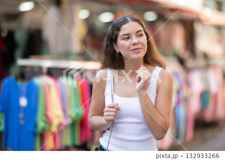 Girl looks at contents of clothes shop window assortment Girl looks at contents of clothes shop window assortment 132933266
