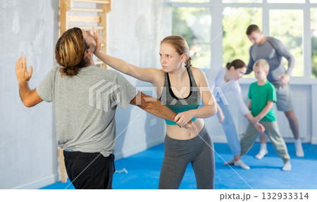 Teen girl in gym perform basic elements of krav maga self-defense system. Teen girl in gym perform basic elements of krav maga self-defense system. 132933314