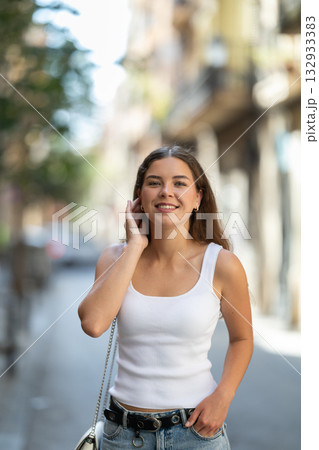 Young woman walks through streets of historic city center. On bright summer day, tourist girl looks at old buildings Young woman walks through streets of historic city center. On bright summer day, tourist girl looks at old buildings 132933383