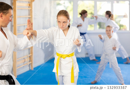 Teen girl is paired with male teacher to learn how to strike and rehearses blocking opponent 132933387