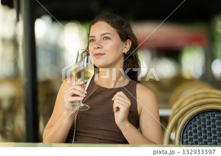 Beautiful woman relaxing and drinking white wine while sitting on terrace of street cafe of Barcelona 132933397