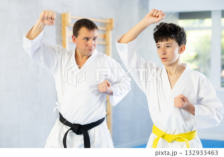 Karate trainer teaching block and punches to teenager in the gym Karate trainer teaching block and punches to teenager in the gym 132933463