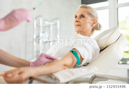 Senior woman getting collecting analysis in clinic. 132933496