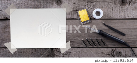 Blank Paper Sheet with Adhesive Tape on Wooden Rustic Table with Soldering Iron and Solder. File with Clipping Path. Blank Paper Sheet with Adhesive Tape on Wooden Rustic Table with Soldering Iron and Solder. File with Clipping Path. 132933614