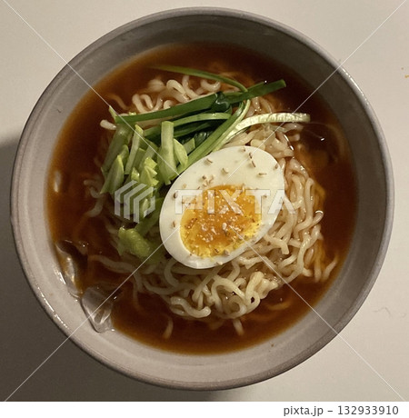 Naengmyeon, a refreshing Korean cold noodle dish served in an icy broth, topped with sliced vegetables, a boiled egg, and spicy sauce. Perfect for summer food photography and Korean cuisine projects. 132933910