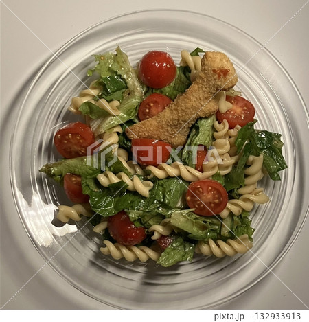 Colorful pasta salad with a mix of fresh vegetables, olives, and herbs, tossed in a light dressing. A refreshing and satisfying dish, perfect for a quick lunch or picnic gathering. 132933913