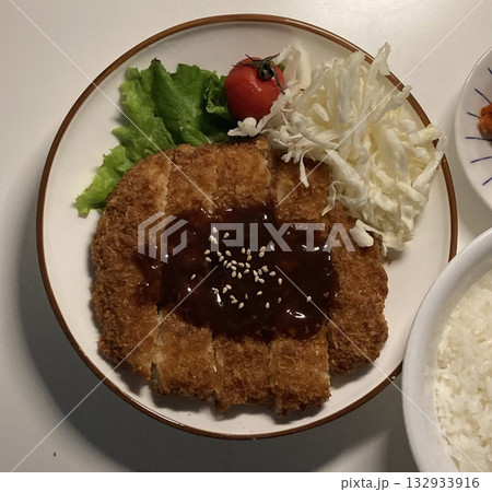 Crispy tonkatsu, a Japanese-style breaded and deep-fried pork cutlet, served with shredded cabbage and drizzled with savory sauce. A delightful balance of crunchy texture and juicy meat. Crispy tonkatsu, a Japanese-style breaded and deep-fried pork cutlet, served with shredded cabbage and drizzled with savory sauce. A delightful balance of crunchy texture and juicy meat. 132933916