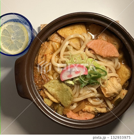 A warm bowl of udon noodles in a savory broth, topped with fresh scallions and tempura. This Japanese comfort food offers a perfect blend of chewy noodles and umami-rich flavors! A warm bowl of udon noodles in a savory broth, topped with fresh scallions and tempura. This Japanese comfort food offers a perfect blend of chewy noodles and umami-rich flavors! 132933975
