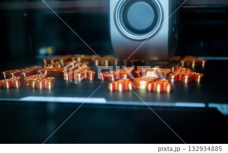 3D printer close up. Working 3D printer in process of printing object from molten orange plastic. 3D printer creating model by flowing liquid plastic from extruder of printer. 3D printing technology 132934885