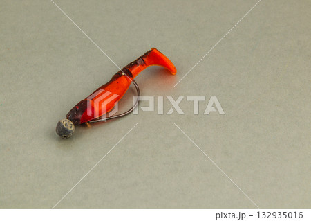 Bright orange fishing lure resting on a smooth surface during daylight hours 132935016