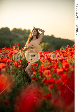 Woman in Poppy Field Holding Straw Hat 132935635