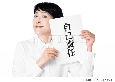 自己責任と書かれた紙を持ちほくそ笑むシニア女性 132936394
