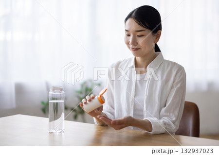 錠剤を飲もうとするミドル女性 132937023