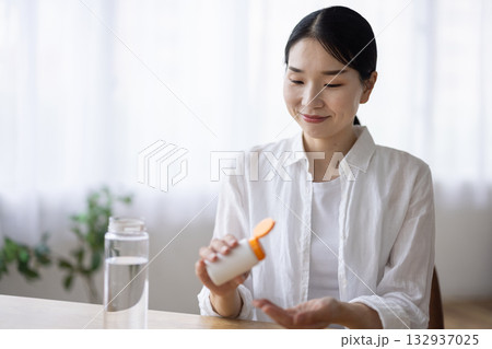 錠剤を飲もうとするミドル女性 132937025