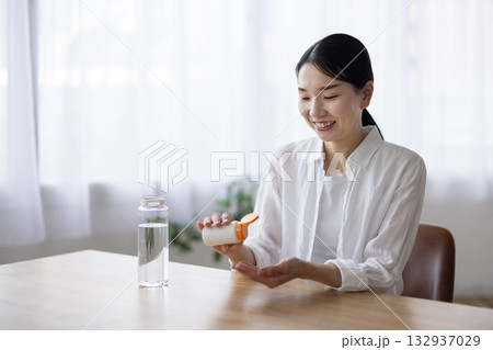 錠剤を飲もうとするミドル女性 132937029