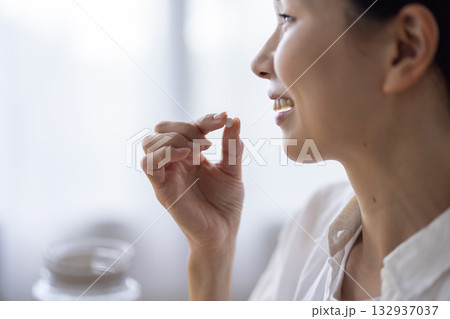 手のひらに取り出されたサプリメントの錠剤とボトルのクローズアップ 132937037