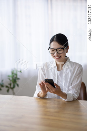 スマートフォンを笑顔で操作するメガネをかけたミドル女性 132937159