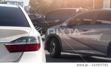 Rear side of white car driving on the road. Two cars cut off the right lane during rush hour in the city. Blurred of trees and city. 132937781